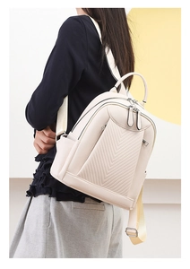 Side view of cream-white faux leather backpack with V-quilted texture on model back