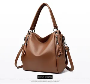 Detail of tan pebble leather tote bag showing tassel zippers and refined texture