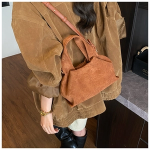 Detail view of a vintage dark brown suede handbag with unique folded texture and strap