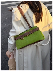 Détail du sac sous le bras en daim vert avec boucle métal et bandoulière contrastée