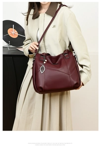 Gros plan du sac cabas bordeaux en similicuir avec pendentif perle sur un mannequin