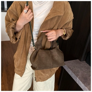 Detail of dark brown suede cloud bag with soft pleats and contrasting green strap