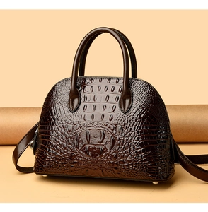 Macro view of burgundy snakeskin texture and double handles on the dome handbag