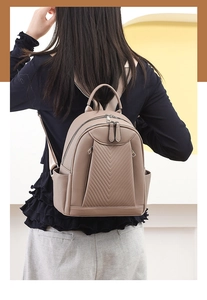Detail of khaki pebbled leather backpack featuring elegant V-shaped quilted stitching