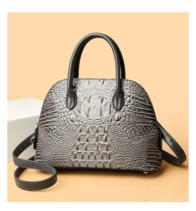 Detailed view of grey crocodile pattern on a shell-shaped handbag with top handles