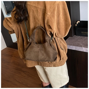 Detail of dark brown suede cloud dumpling bag with elegant green leather shoulder strap