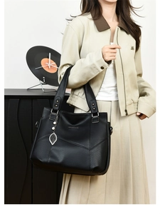 Détail du sac cabas en cuir noir texturé avec breloque feuille et logo métallique