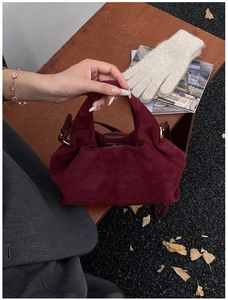 Detailed macro view of a burgundy suede cloud bag with soft pleats and metal buckle