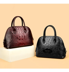 Close-up of crocodile-embossed shell bags in wine red and black with metal base studs