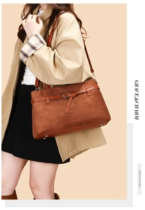 Detail of brown suede tote bag featuring smooth leather trim and metal buckle accent