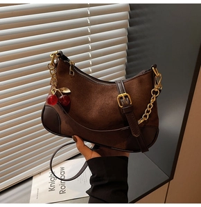 Detail of hobo bag in brown matte leather with gold lock and cherry metal charms