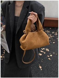 Detailed shot of brown suede dumpling bag with pleated texture and adjustable strap