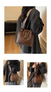 Detail view of woven bucket bag with patterned wide strap and brown leather texture
