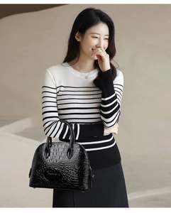 Detail of glossy black faux crocodile skin texture on shell-shaped handbag with silver hardware