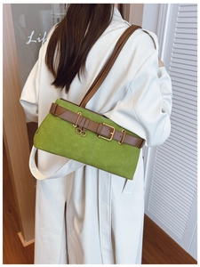 Détail du sac à bandoulière en daim vert avec bride en cuir marron et boucle dorée