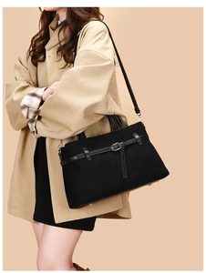 Side view of black matte suede tote bag on a model wearing a beige trench coat