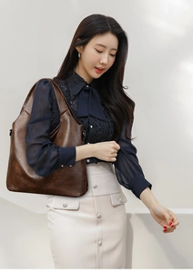 Close-up of deep brown lychee texture leather tote bag with stylish integrated handle