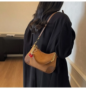 Bruine suède hobo tas met gouden ketting en kersenhanger getoond op model rugzijde