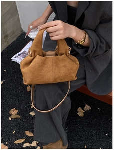 Detail of caramel brown dumpling bag with pleats, gold hardware, and suede texture