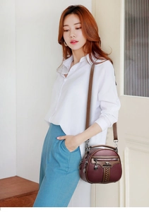Burgundy textured leather crossbody bag with kangaroo logo shown on a model