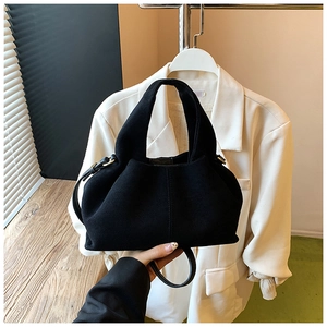 Close-up of a black matte cloud bag with a top handle and a slim crossbody strap