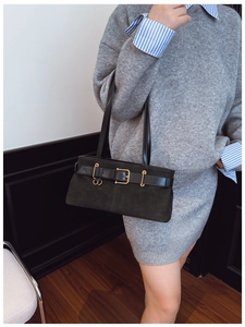 Détail du sac sous l'aisselle en daim noir avec boucle dorée et lanière en cuir