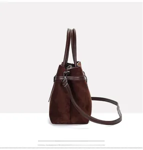 Detail view of the matte suede texture and brown leather strap on this tote bag