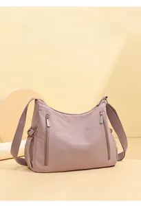 Detail view of pink Oxford cloth crossbody bag with multi-layer zippers and side pockets