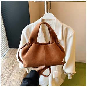 Detail of soft brown suede dumpling bag with vertical stitching and leather strap