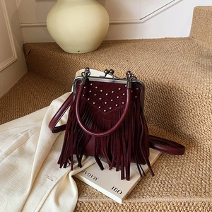 Close-up of vintage burgundy crossbody bag with silver studs and long fringe details