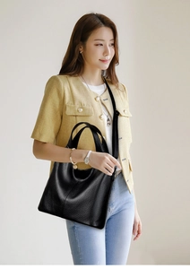 Detail of minimalist black leather tote bag with dual handles and wide shoulder strap