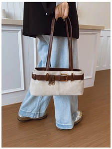 Détail d'un sac à bandoulière crème chic avec des lanières marron foncé et boucle en métal