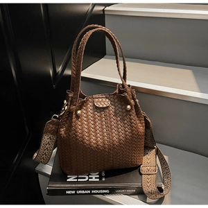 Close-up of caramel woven bucket bag with patterned strap and golden metal hardware