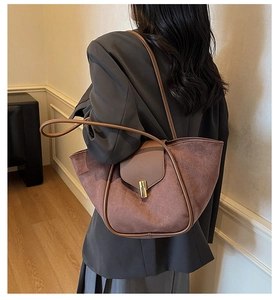 Close-up of chocolate brown suede tote bag featuring a minimalist gold twist lock closure