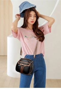 Detail of black pebbled leather crossbody bag with brown trim and kangaroo brand logo