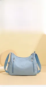 Detail of light blue Oxford cloth crossbody bag with multi-layer zippers and side pockets