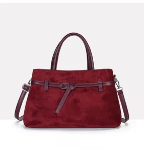 Detail of burgundy tote bag featuring matte suede texture and smooth leather strap