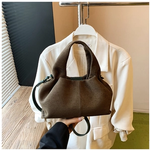 Detail of dark brown matte suede bucket bag with unique pleated texture and green strap