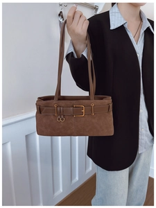 Détail d'un sac à bandoulière marron mat avec boucles de ceinture décoratives et anneaux