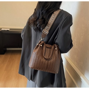 Detail of woven brown bucket bag with vintage ethnic pattern jacquard strap and gold hardware