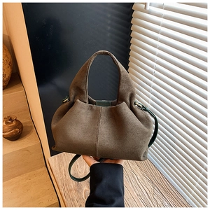 Detail of brown suede dumpling bag with green lining and metal ring attachment