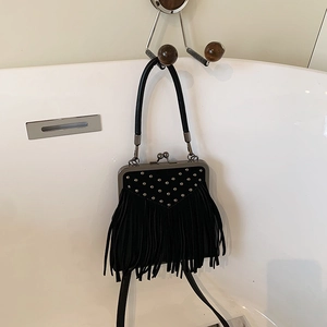 Detail of black suede fringe bag with silver studs and metal clasp handle