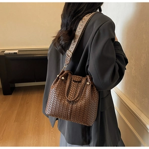 Detail of a brown woven bucket bag featuring a decorative colorful wavy shoulder strap