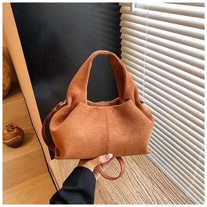 Detail of camel brown suede cloud bag with adjustable strap in soft natural window light
