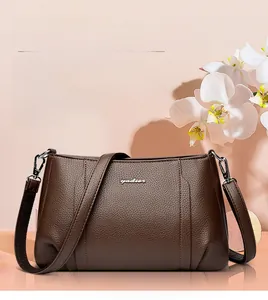 Detail of dark brown litchi pattern leather crossbody bag with metallic logo