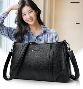 Detail of black pebbled leather crossbody bag with silver hardware and logo
