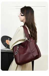 Sac cabas bordeaux avec texture litchi et pendentif feuille en métal sur modèle