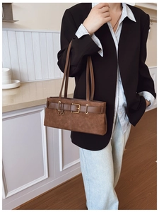 Détail d'un sac porté épaule en daim marron vintage avec boucle décorative en métal