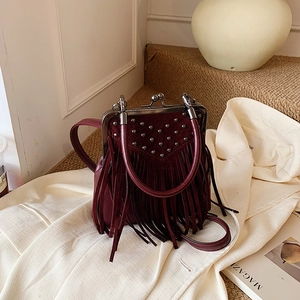 Close-up of wine red bag featuring metallic V-shaped studs and flowing long tassels