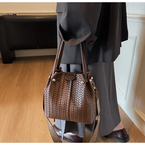 Detail of brown woven bucket bag featuring premium leather texture and patterned strap